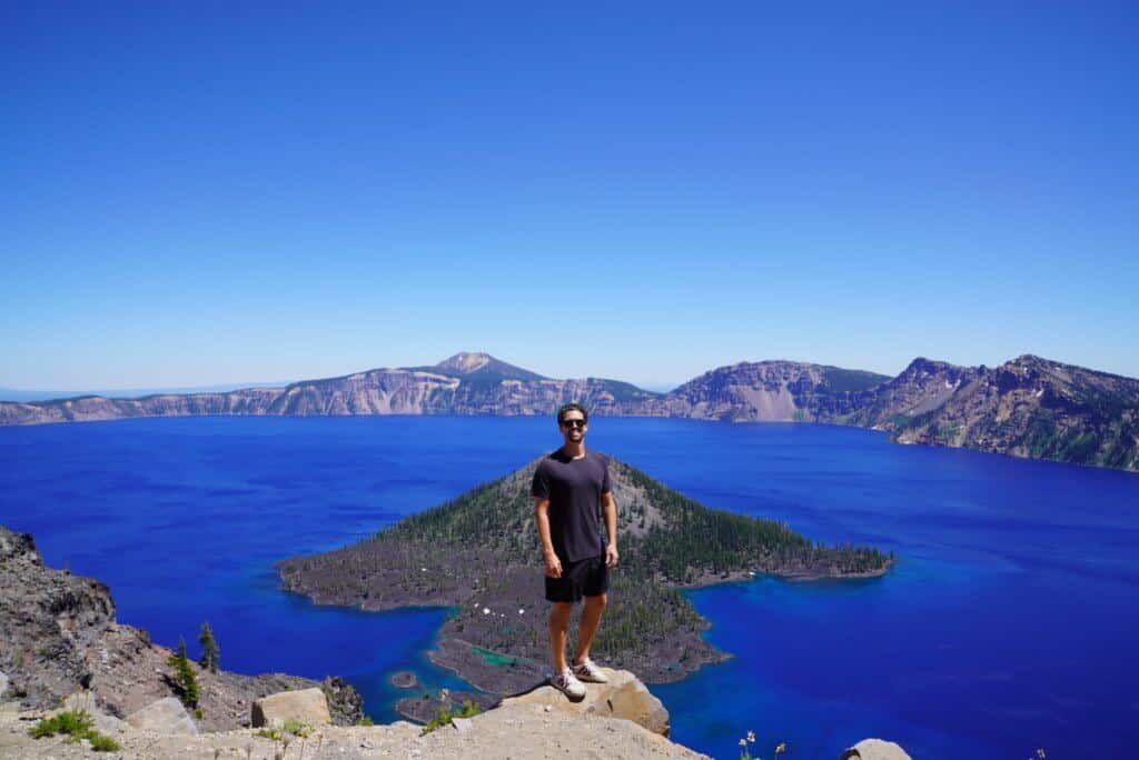 a man stands at crater lake on road trip during covid-19 pandemic