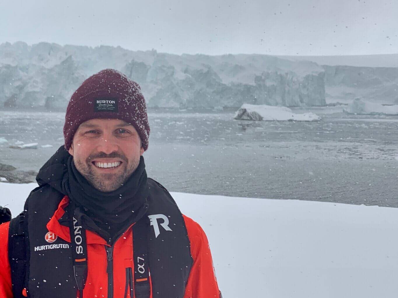 man in snow with glacier in antarctica