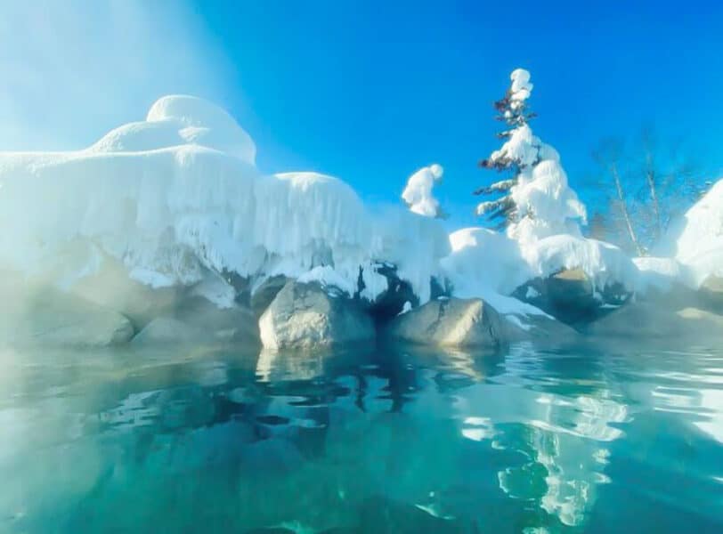 steam rising from natural hotspring pool surrounded by snow