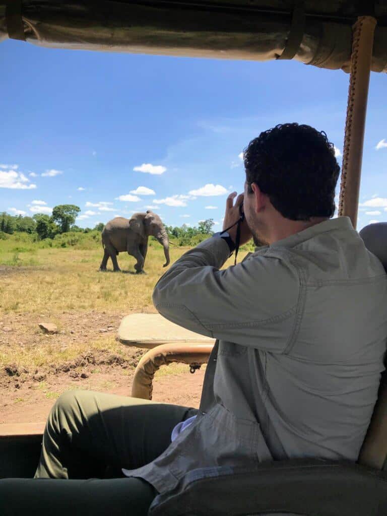 A tourist takes photos of an elephant while on safari