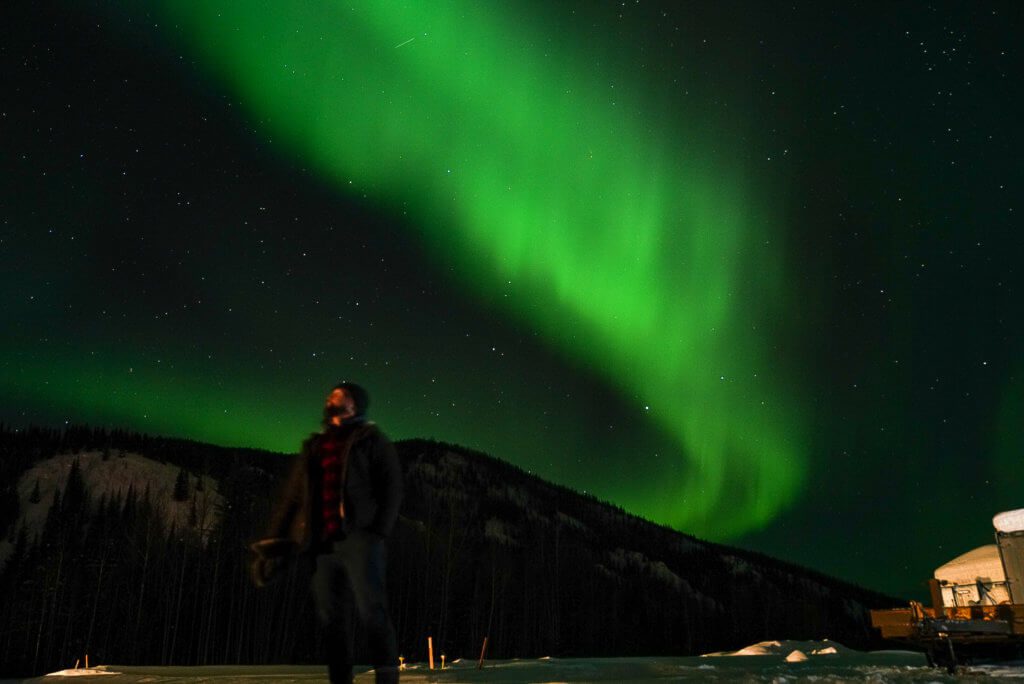 A man looks at the green northern lights in Alaska