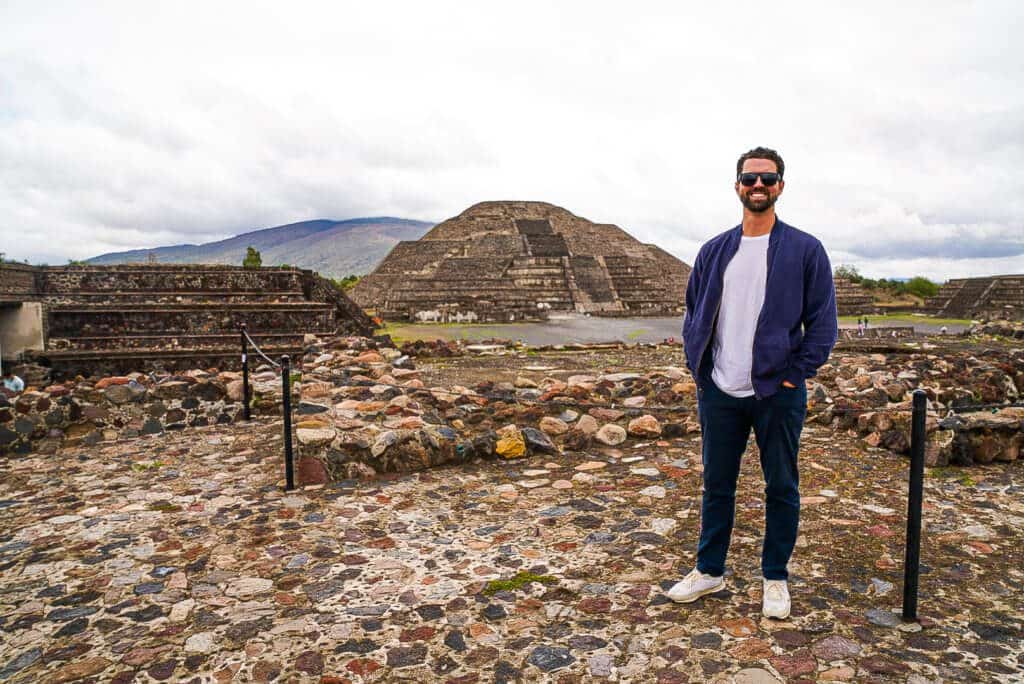 man stands in front of pyramids of teotihuacan in mexico 
