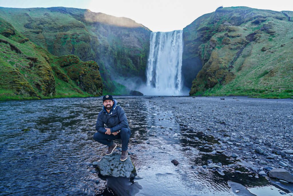 man in front of skogafoss waterfall iceland south coast