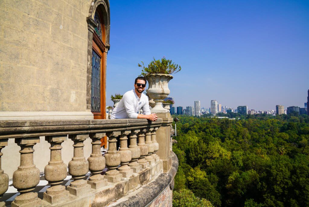 man on balcony of chapultepec castle with mexico city skyline from 