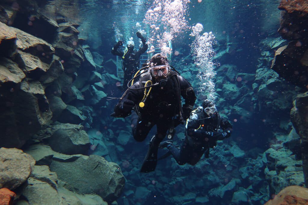 man scuba diving between two continents in silfra fissure iceland