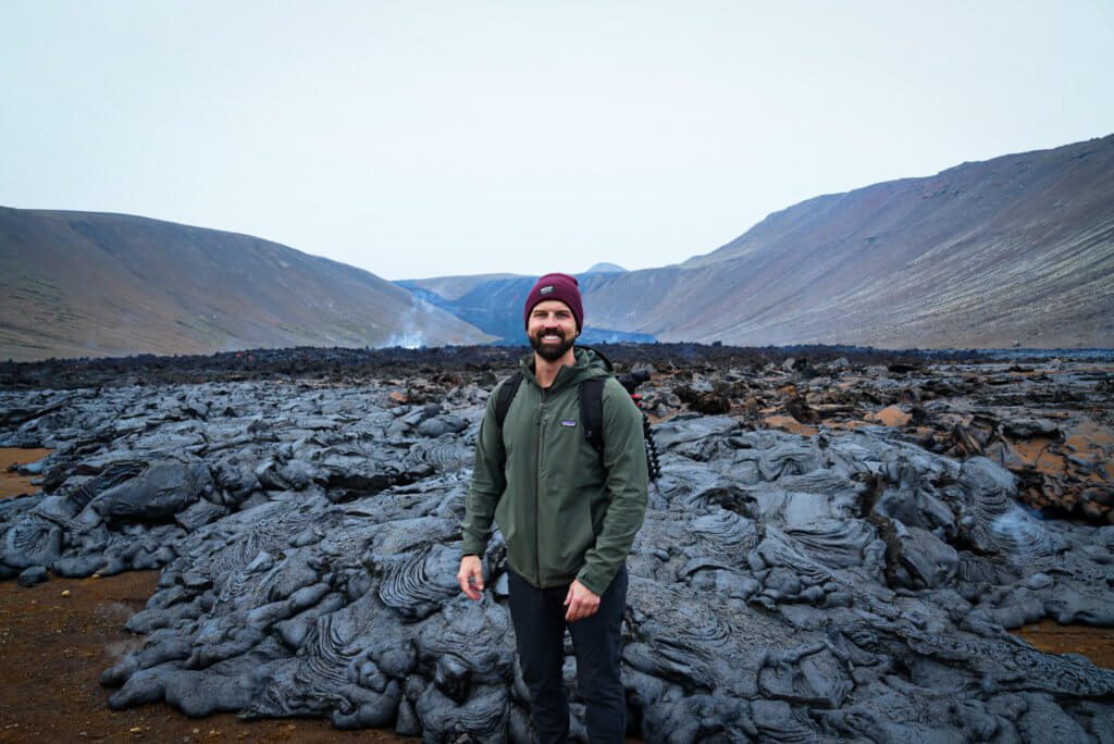 man stands in front of cooled black lava 