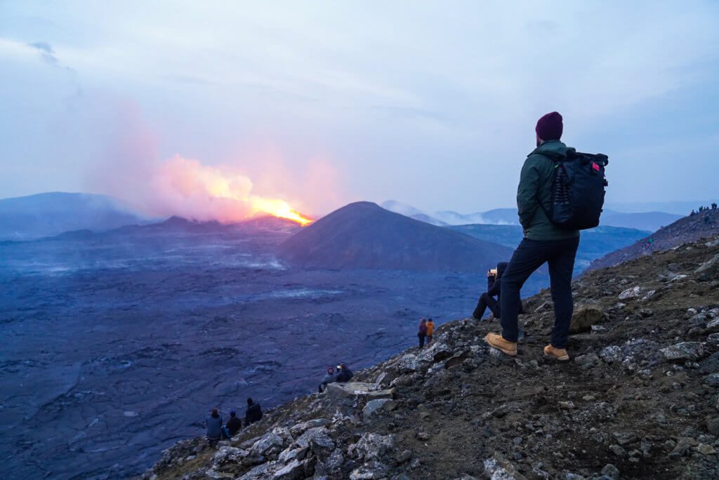 man stands in front of an erupting volcano in 