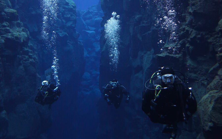 people drysuit diving between two continents in silfra iceland
